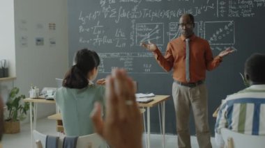 Afrikalı Amerikalı profesör üniversitede ders sırasında öğrencilerin sorularını yanıtlıyor