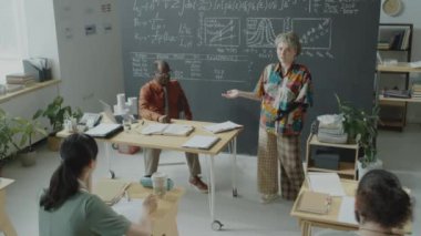 Protez kollu bir kız öğrencinin karatahtadaki grafikleri ve formülleri gösterirken ve üniversite dersi sırasında grup arkadaşlarıyla ve Afrikalı Amerikalı profesörlerle konuşurken çekilen görüntüleri.