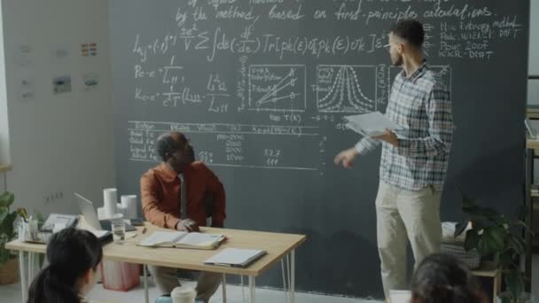 Dwurasowy Student Trzymający Notatnik Wyjaśniający Formuły Wykresy Tablicy Grupowej Afroamerykańskiej — Wideo stockowe