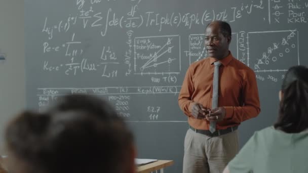 Gammal Afroamerikansk Professor Står Vid Tavlan Klassrummet Och Förklarar Matematik — Stockvideo