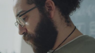 Gözlüklü, sakallı, çift ırklı öğrencinin üniversitede ders sırasında konuşma yaparken yakın plan fotoğrafı.