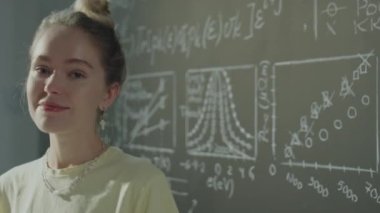 Üniversite sınıfında gülümseyen ve kameraya poz veren neşeli kız öğrencinin portresi