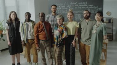 Çok ırklı öğrencilerin ve Afro-Amerikan profesörün grup portresini, üniversite sınıfında kameraya birlikte poz vererek büyütün.