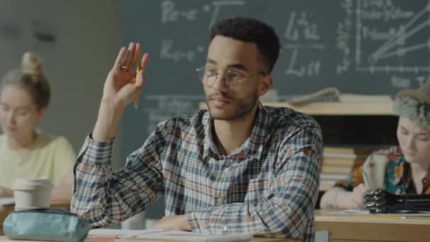 Junge Männliche Studenten Sitzen Klassenzimmer Schreibtisch Heben Den Arm Und — Stockvideo