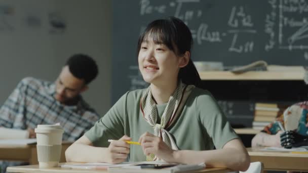 アジアの女性学生が腕を上げて質問し 高校での授業中にメモを取る — ストック動画