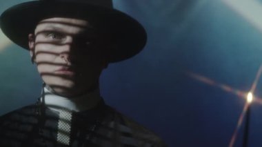 Cüppeli ve şapkalı genç rahibin ışık yansıtmalı bir mumla stüdyoda durduğu göğüs yukarı.