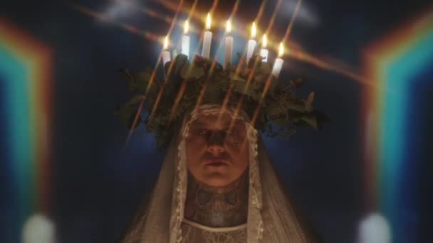 キャンドルライトの花輪とベールを持つクィアの男の肖像は 背景に点滅光と万華鏡投影と暗いスタジオでカメラのためにポーズ — ストック動画