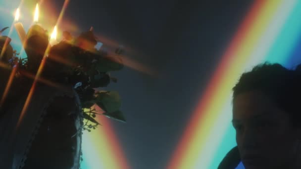 サイドビューバックライト虹の光の投影と暗いスタジオで一緒にヤシの木と祈る帽子とキャソックで司祭のショット — ストック動画
