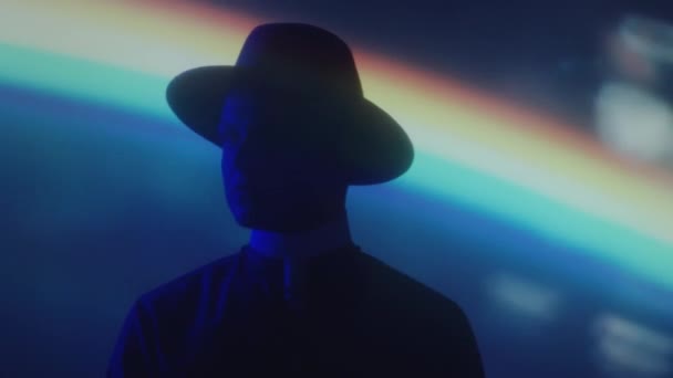Silhouette Man Fedora Hat Standing Dark Studio Rainbow Light Projection — Stock Video