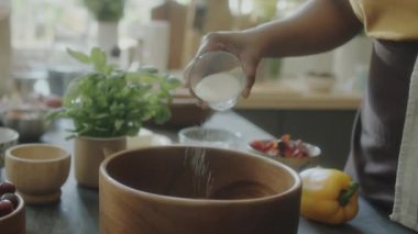 Afrika kökenli Amerikalı kadının ahşap kaseye tuz ekleyip mutfakta yemek hazırlarken çekilmiş el kamerası görüntüleri.