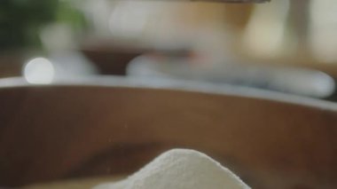 Unu, çelik elek bardağıyla kase içine eleme sahnesini yakından çek.