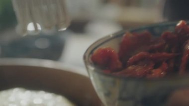 Fırıncının, güneşte kurutulmuş domateslerden zeytinyağı sürerek ahşap kasede silikon fırçayla hamura yaptığı görüntüyü kapatın.
