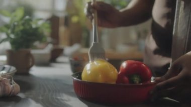Pişirmeden önce siyah biberleri silikon fırçayla yağlayan Afrikalı Amerikalı bir kadın.