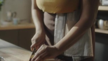 Afrika kökenli Amerikalı bir kadının ahşap tahtada bıçakla domates keserken ve yemek blogu için yemek videosu çekerken kamera önünde konuşurken yakın plan çekimi.