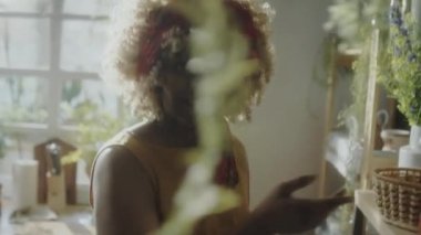 Afro-Amerikalı kadın yemek blogcusunun yemek pişirme fırını açtığı ve yemek pişirmeden önce kameranın önünde konuştuğu el kamerası görüntüleri.