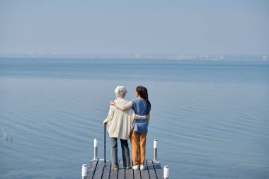 Kıdemli kadın ve torununun engin mavi göl ve gökyüzünün önünde dikiz aynasından bakan ve hafta sonunun keyfini çıkaran