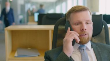 İş günü resmi kıyafet giymiş bir erkek ofis çalışanının cep telefonuyla konuşması.
