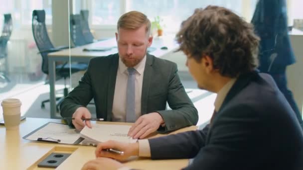 オフィスミーティング中の事業報告を議論する正式な訴訟における2人の男性同僚 — ストック動画