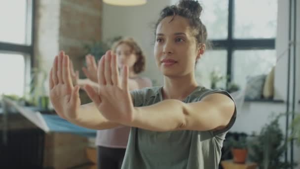 在练习室集体练习瑜伽时 一位美丽的黑发女子伸出胳膊 弯曲手腕的选择性聚焦镜头 — 图库视频影像