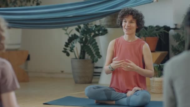 Yogalehrerin Sitzt Mit Überkreuzten Beinen Auf Matte Und Plaudert Mit — Stockvideo