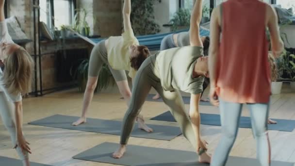 在集体瑜伽课上 女指导员帮助女性做长三角姿势 — 图库视频影像
