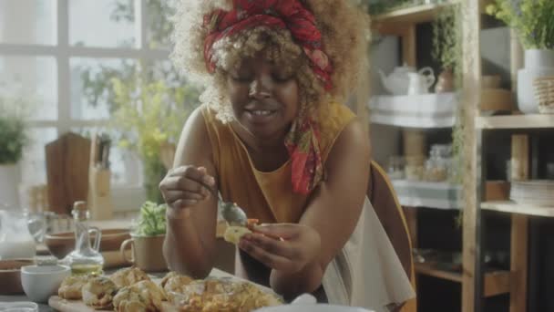 Африканська Американська Жінка Кладе Топінг Смачну Домашню Булочку Їсть Розмовляє — стокове відео