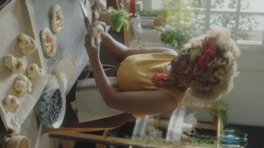 Mutfak masasında hamuru yuvarlayan kadın fırıncının dikey yakın çekimi.