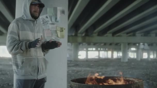 放棄された建物に立って手を火の玉で暖めるホームレスの男 — ストック動画