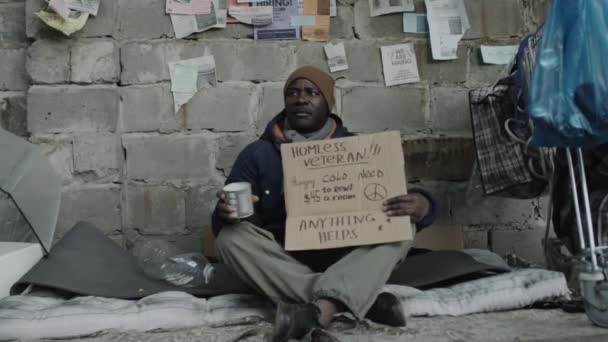 Afroamerikansk Hemlös Tiggare Sittandes Marken Med Papp Skylt Och Metall — Stockvideo