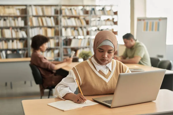 Estudante Muçulmano Usando Laptop Estudo Enquanto Senta Mesa Biblioteca — Fotografia de Stock