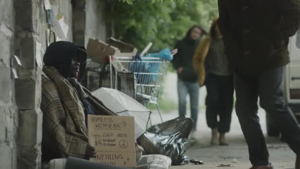 Afroamerikanischer Straßenbettler Sitzt Mit Pappschild Und Metallbecher Als Passant Auf — Stockvideo