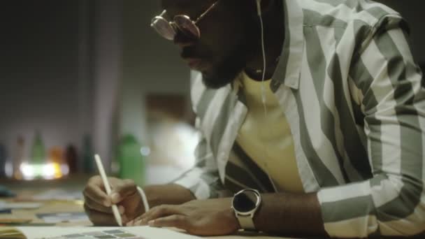 Diseñador Afroamericano Auriculares Moviendo Cabeza Música Dibujando Copybook Mientras Trabajaba — Vídeo de stock