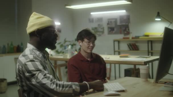 Asiatiska Och Afroamerikanska Manliga Designers Diskuterar Något Datorskärmen Medan Arbetar — Stockvideo