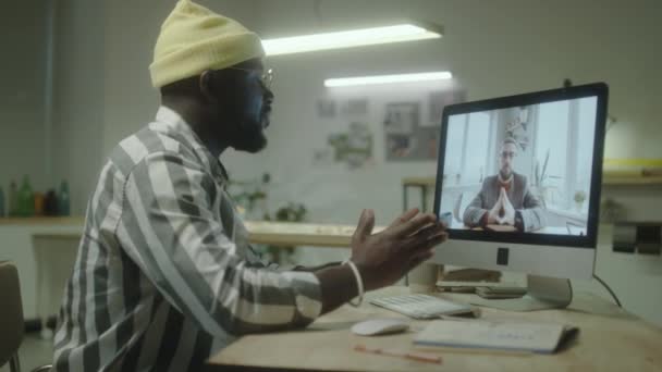 在工作到很晚的时候 非洲裔美国设计师通过计算机视频电话与男性同事讨论项目 — 图库视频影像
