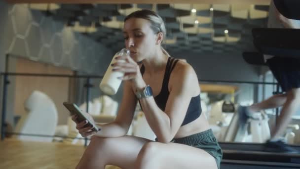 Жінка Спортивному Одязі Сидить Спортзалі Воду Пляшки Використовує Мобільний Телефон — стокове відео