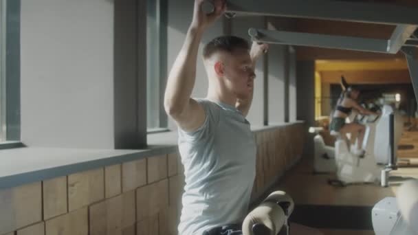 운동복 차림의 근육질 남자가 헬스클럽에서 기계를 사용하는 — 비디오