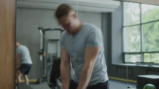 体育館で仕事をしながらケトルベルスイング運動をするスポーツウェアの筋肉の男 — ストック動画