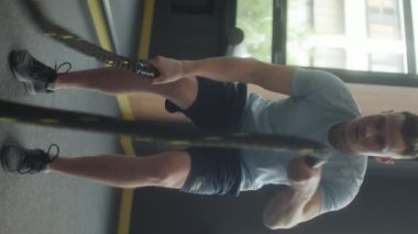 Spor kıyafetli bir sporcunun spor salonunda egzersiz yaparken dikey çekimi.