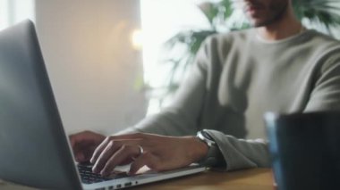Çalışma saatlerinde genç bir adamın laptopta yazı yazışının seçici odak fotoğrafını kapat.