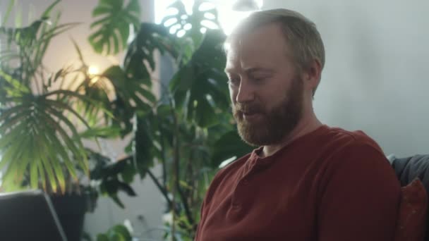 Sakallı Beyaz Bir Adam Evdeki Koltukta Oturuyor Bilgisayarında Uzaktan Çalışırken — Stok video