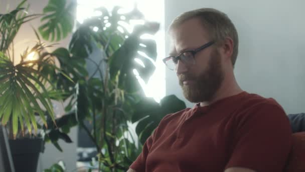 Снимок Молодого Бородатого Мужчины Сидящего Диване Разговаривающего Интернету Работающего Ноутбуке — стоковое видео