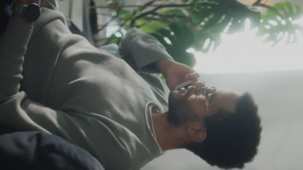 Plan Vertical Jeune Homme Assis Sur Canapé Parlant Sur Téléphone — Video