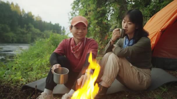 Two Asian Female Tourists Resting Bonfire Tent Holding Steel Tea — Stock Video