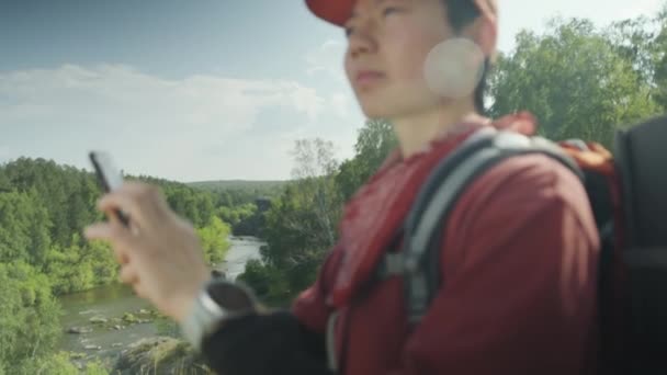 亚洲女性游客背着背包站在国家公园里 在远足过程中使用手机和智能导航 拍了一张中等特写照片 — 图库视频影像