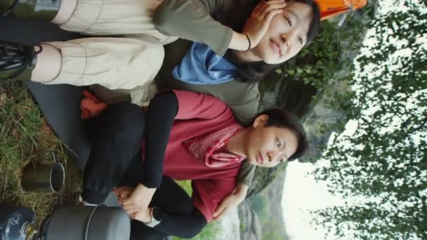 亚洲女同性恋夫妇坐在营地的帐篷旁 一边做饭一边拥抱和聊天的垂直镜头 — 图库视频影像