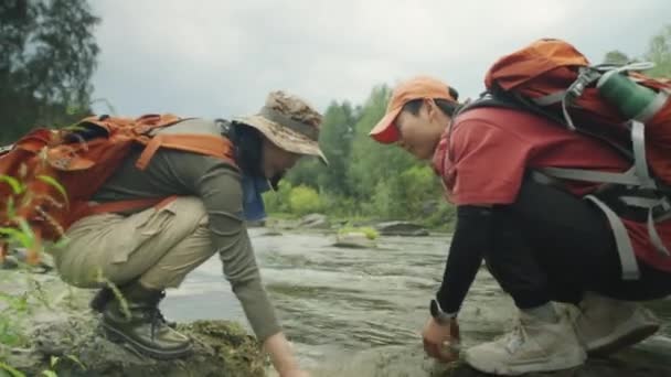 Sidovy Två Asiatiska Kvinnliga Turister Som Hukar Stenar Flodstranden Och — Stockvideo