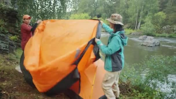 Two Asian Female Tourists Covering Tent Tarp While Camping River — Stock Video