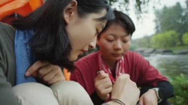 Nehir kenarındaki kamp alanında yemek yerken iki Asyalı kadın turistin sıcak yemek yediği yakın çekim.