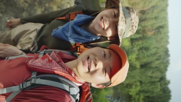 二つの幸せなアジアの女性観光客の垂直ショット手を振って カメラで話しながら旅行Vlogやビデオ通話を撮影 — ストック動画