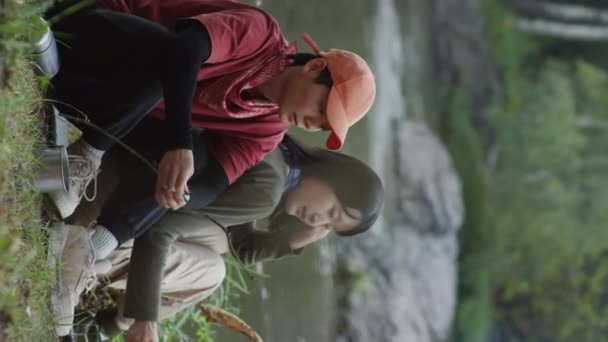 Вертикальный Снимок Двух Азиатских Туристов Разговаривающих Поддерживающих Огонь Ветками Кемпинге — стоковое видео